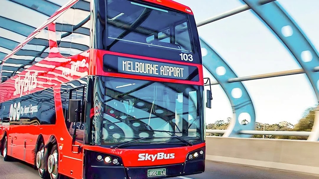 Skybus double-decker heading to Melbourne Airport on a highway bridge.