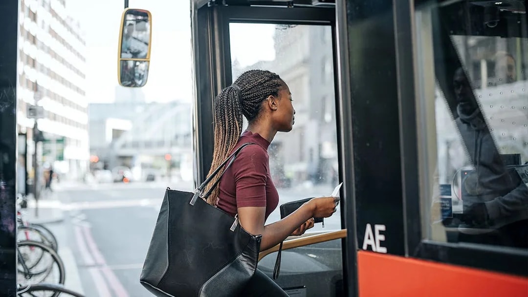 Person boarding a city bus with a Sky-Bus One-Way Transfer Travel Pass.