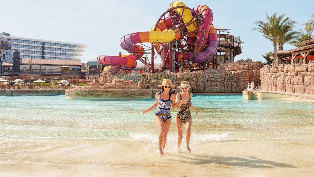 Visitors enjoying a water ride at Meryal Waterpark with colorful slides in the background.
