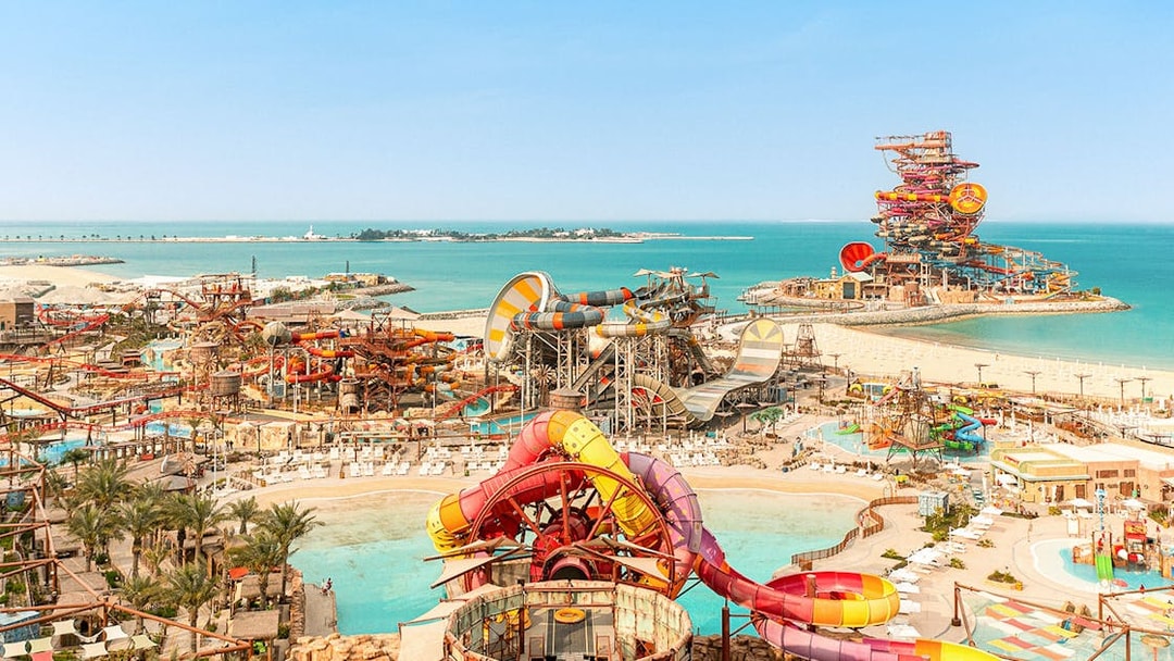 Aerial view of colorful water slides and pools at Meryal Waterpark by the sea.
