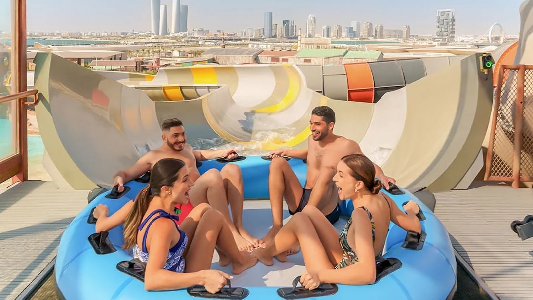 Visitors enjoying a group water ride at Meryal Waterpark with city skyline in background.