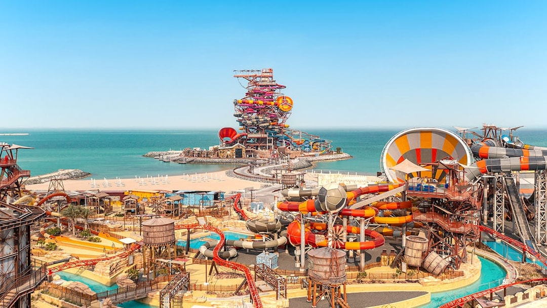 Aerial view of colorful water slides at Meryal Waterpark by the sea.