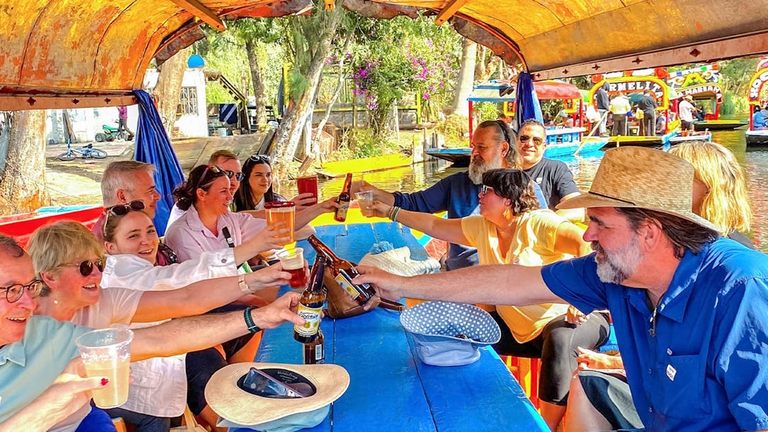 Group enjoying drinks on a colorful boat during Xochimilco tour in Mexico City.