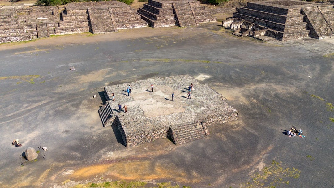 Aerial view of tourists exploring the Avenue of the Dead, Teotihuacan, with pyramids in the background.