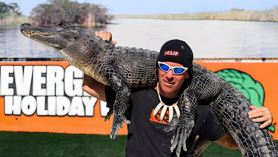 Man holding an alligator at Holiday Park during airboat tour and wildlife show.