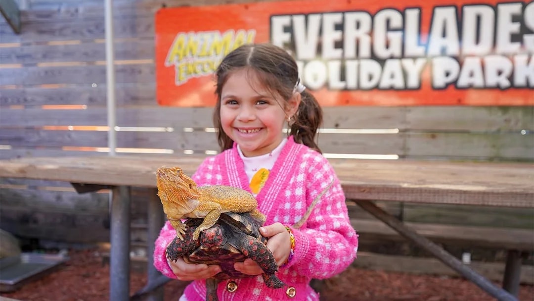 Child holding a lizard and turtle at Everglades Holiday Park animal encounter.