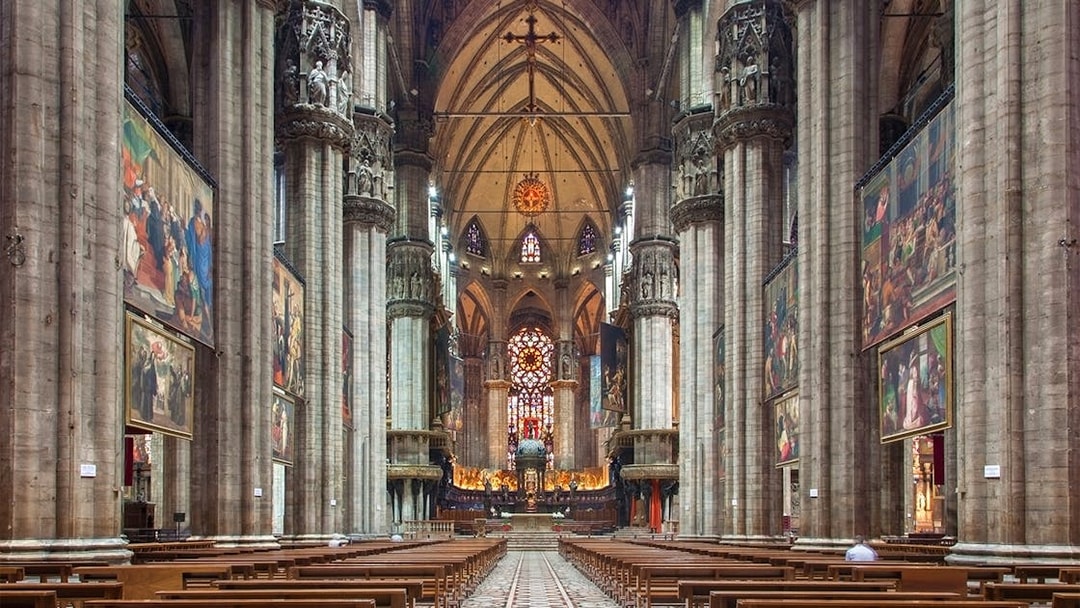 Interior of Milan Duomo with stained glass windows and ornate columns.