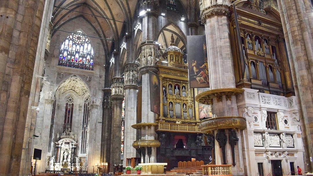 Interior view of Duomo Milan Cathedral featuring ornate columns and stained glass windows.