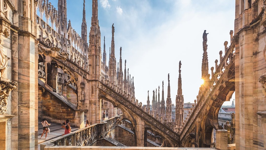 Visitors exploring the rooftop terrace of Milan Duomo Cathedral with spires in view.