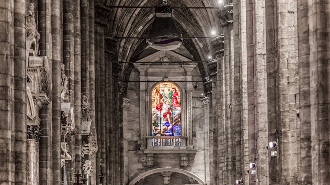 Stained glass window and stone columns inside Duomo Cathedral, Milan.