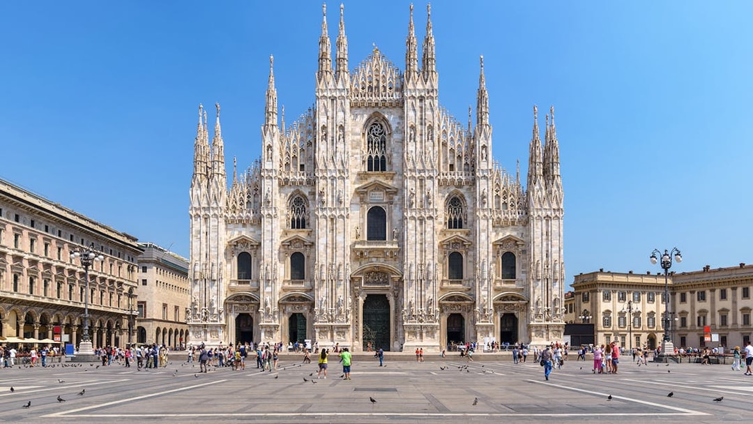 Duomo Milan Cathedral facade with tourists exploring architectural details.