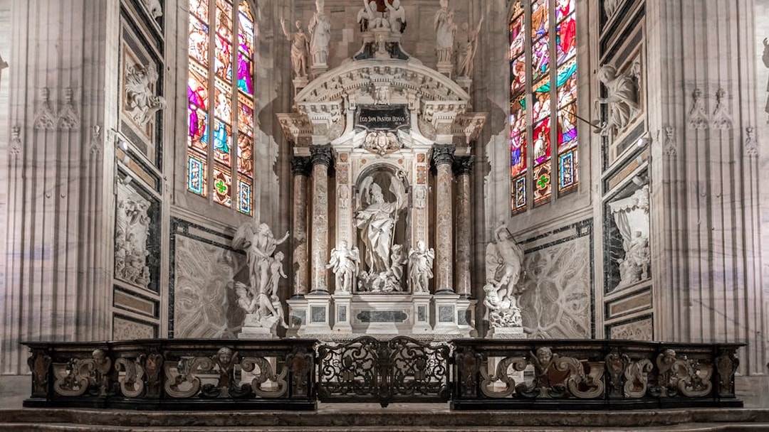 Duomo Cathedral Milan interior with ornate columns, detailed ceiling, and stained glass windows.