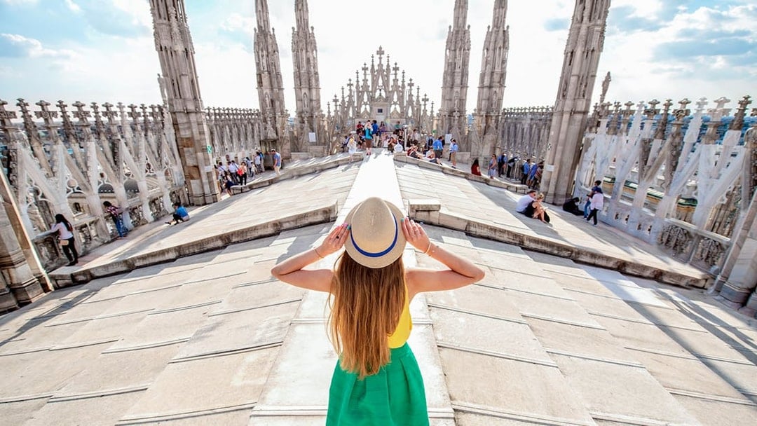 Girl on Milan Duomo rooftop terrace with spires in view.