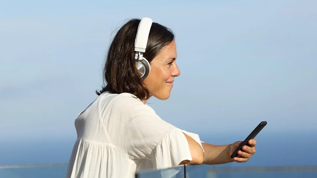 Woman listening to audio guide on cruise deck with ocean view.