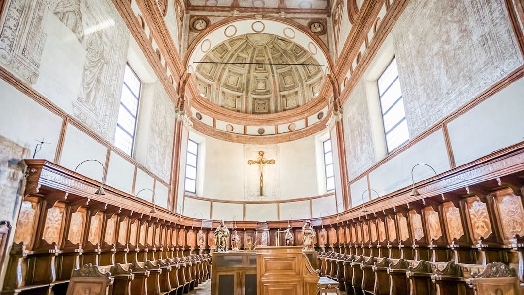 Interior of Santa Maria Delle Grazie Church with wooden choir stalls and a crucifix.