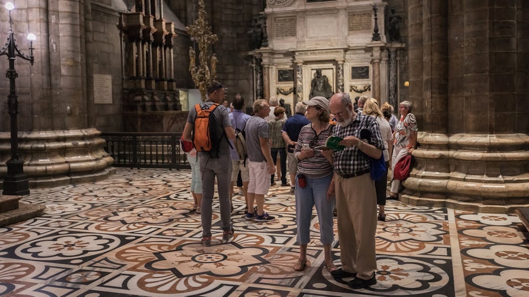 Tourists exploring the interior of Milan Duomo with intricate floor designs.