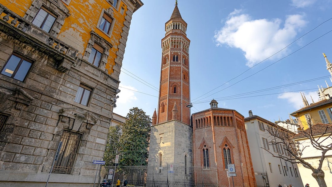 Brick tower near Milan Duomo, Italy, with surrounding historic buildings.