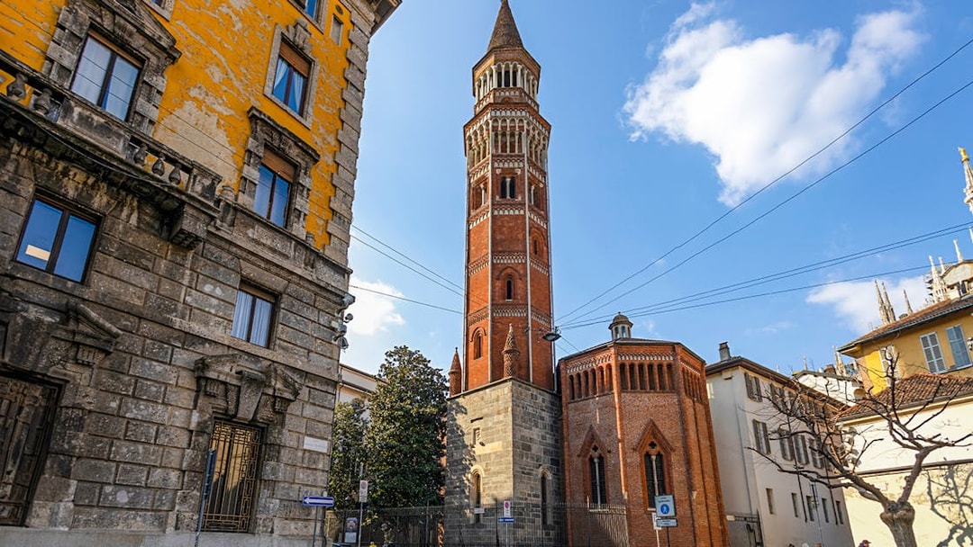 Church of St Gottardo's red brick tower in Milan with surrounding buildings.