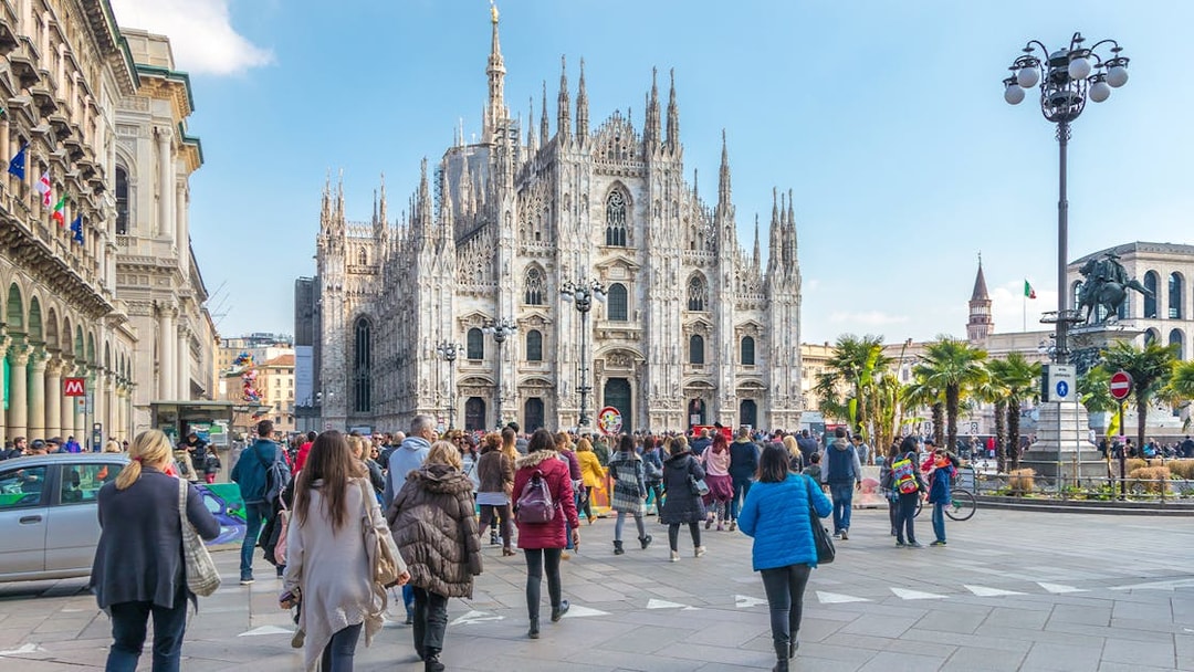 Tourists on Milan Hop-On Hop-Off bus tour with Milan Duomo in view.