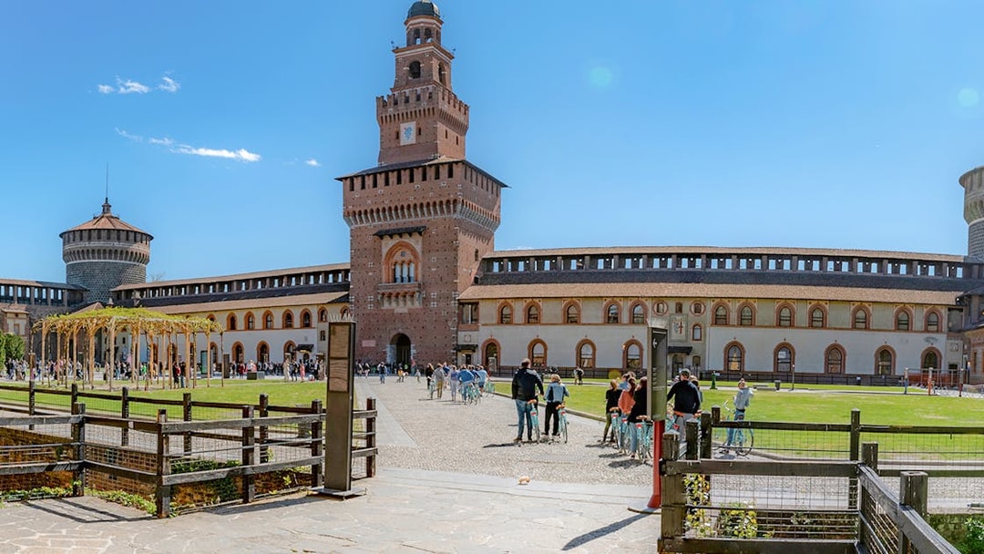 Courtyard of Sforza Castle in Milan with tourists and historic architecture.