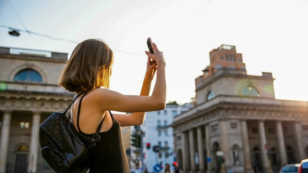 Person taking a photo of historic building in Milan during self-guided audio tour.