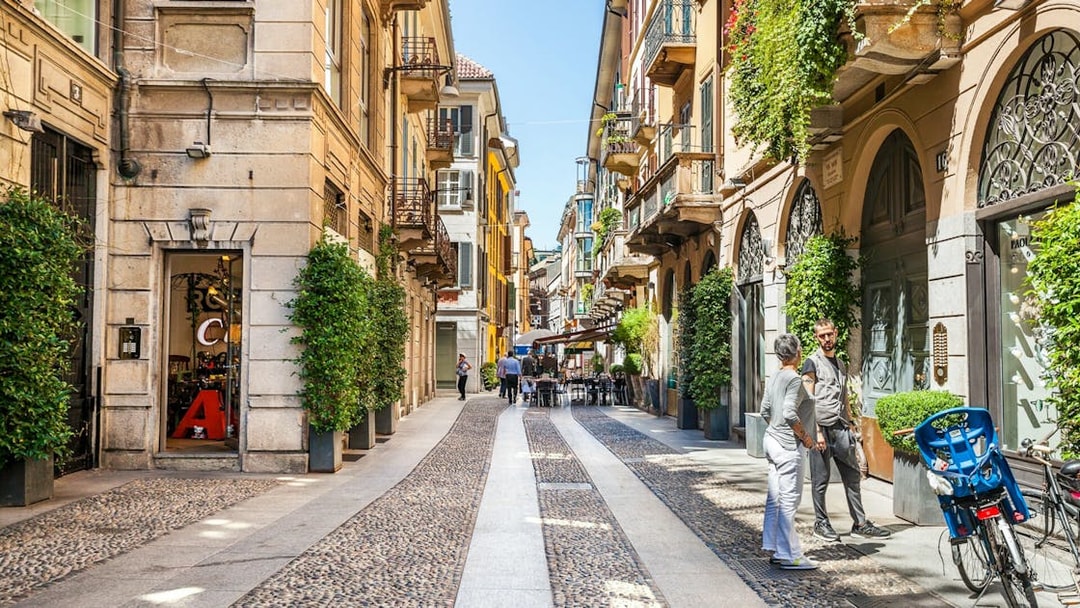 Milan street with cobblestones, outdoor cafes, and historic buildings on a self-guided audio tour.