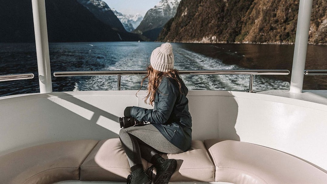 Lady on a boat viewing Milford Sound fjords in New Zealand.