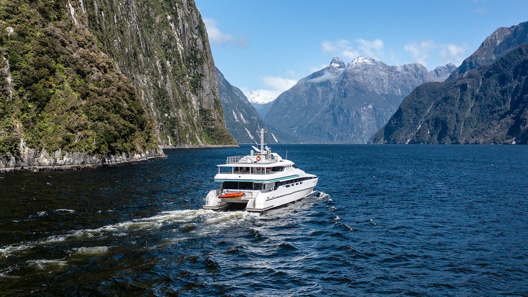 Cruise ship sailing through Milford Sound with mountain views.