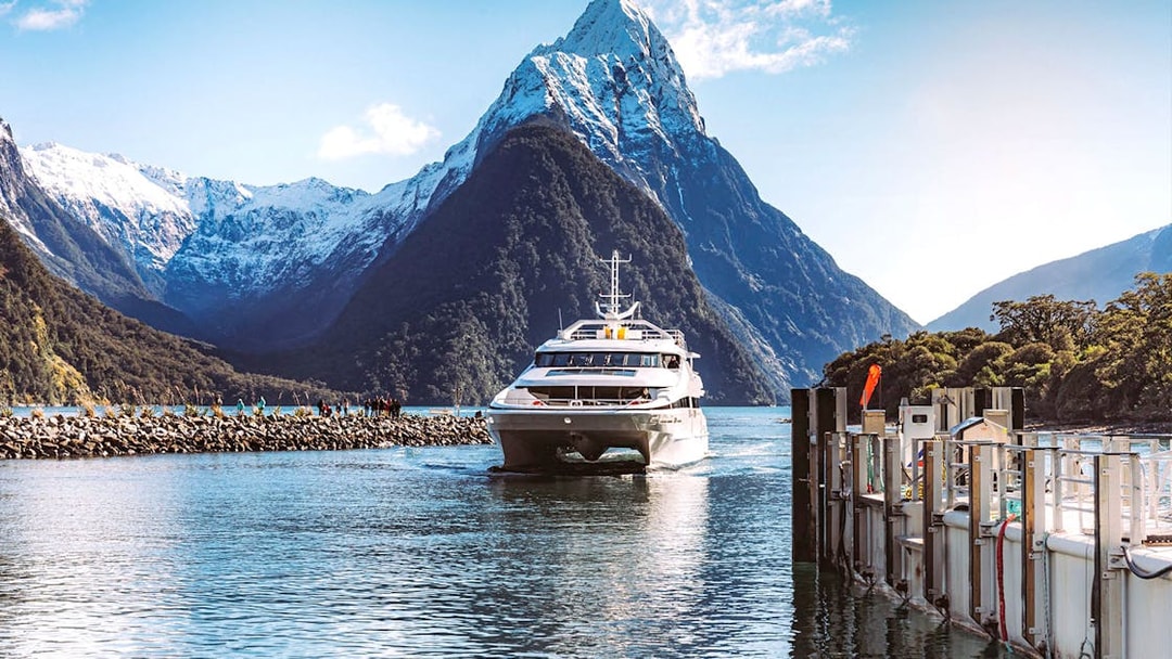 Cruise ship approaching dock with Mitre Peak in Milford Sound, New Zealand.