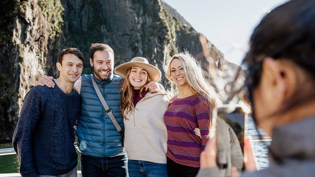Group enjoying a 2-hour cruise on Milford Sound with scenic cliffs in the background.