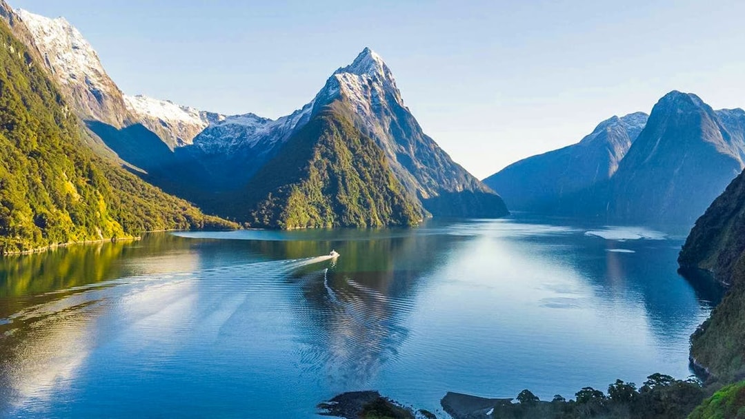 Cruise ship in Milford Sound fjords, New Zealand, with tourists enjoying canapes and champagne.