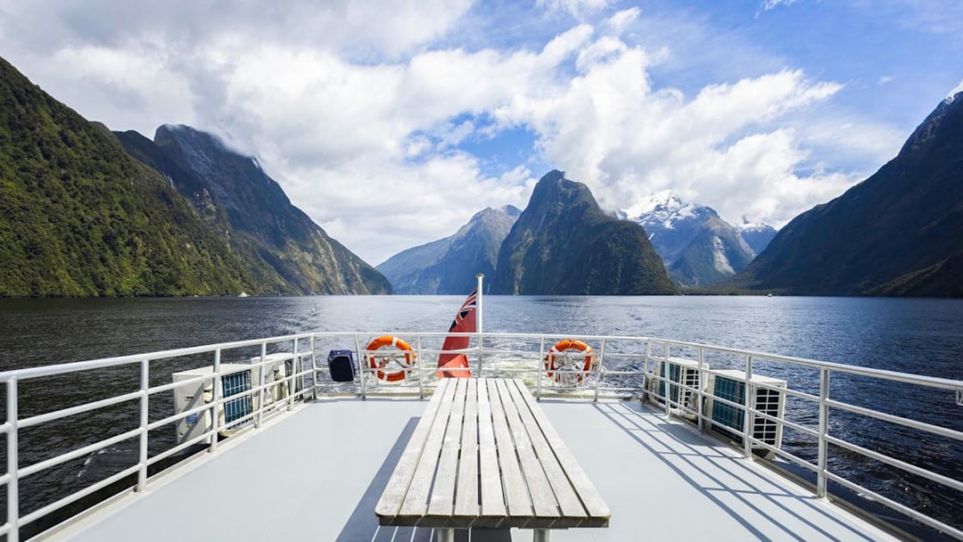 Cruise deck view of Milford Sound fjords in New Zealand with clear skies.