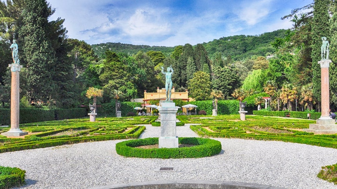 Miramare Castle Garden with statues and manicured hedges in a lush green setting.