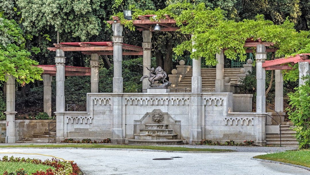 Fountain and sculptures in the garden of Miramare Castle, surrounded by greenery.