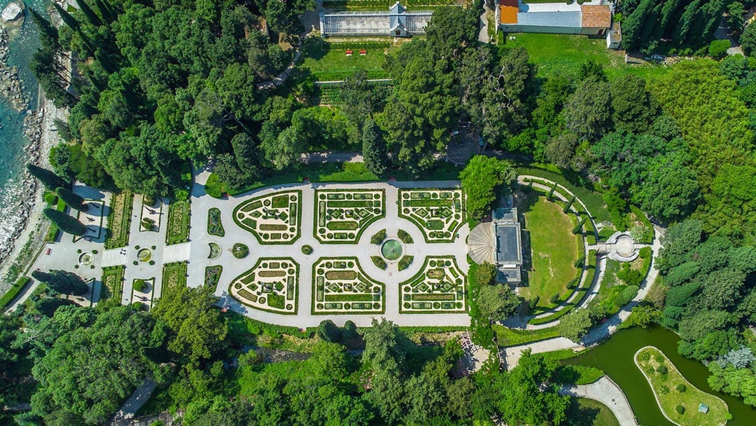 Aerial view of Miramare Castle gardens in Trieste, Italy, showcasing intricate landscaping and pathways.