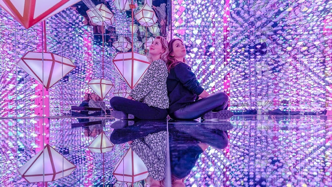 Visitors in mirrored room with colorful lights at Studio Irma, Moco Amsterdam.