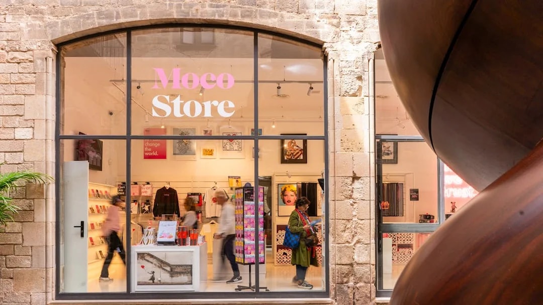 Moco Museum merchandise store entrance in Barcelona with art displays and visitors.
