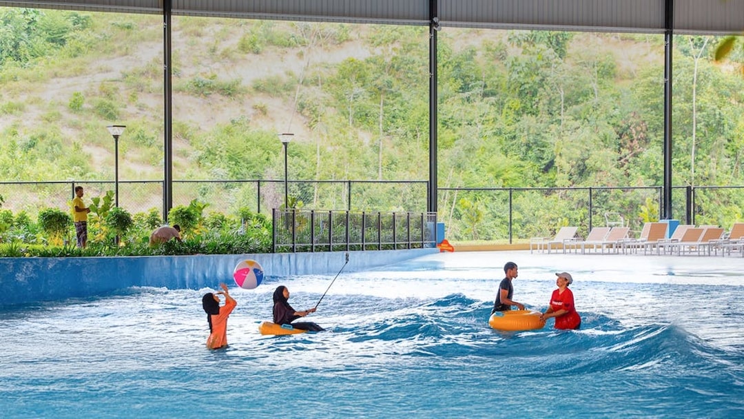 Children enjoying a wave pool with inflatable tubes and a beach ball.
