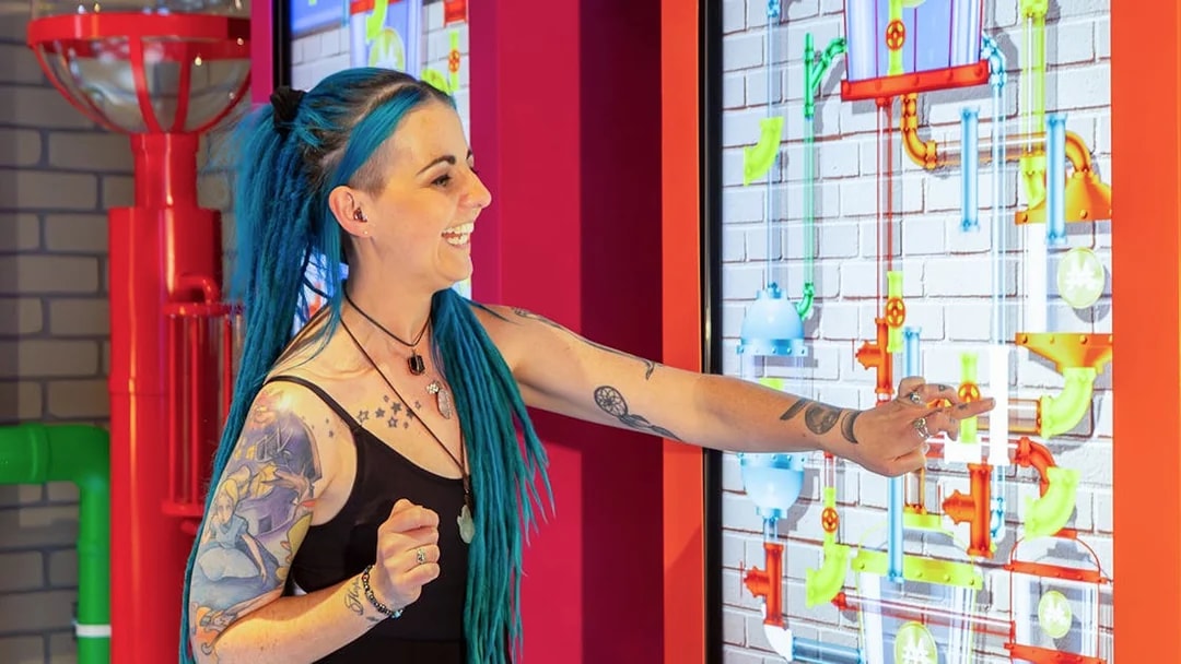 Person interacting with a Monopoly Dreams Melbourne exhibit touchscreen.