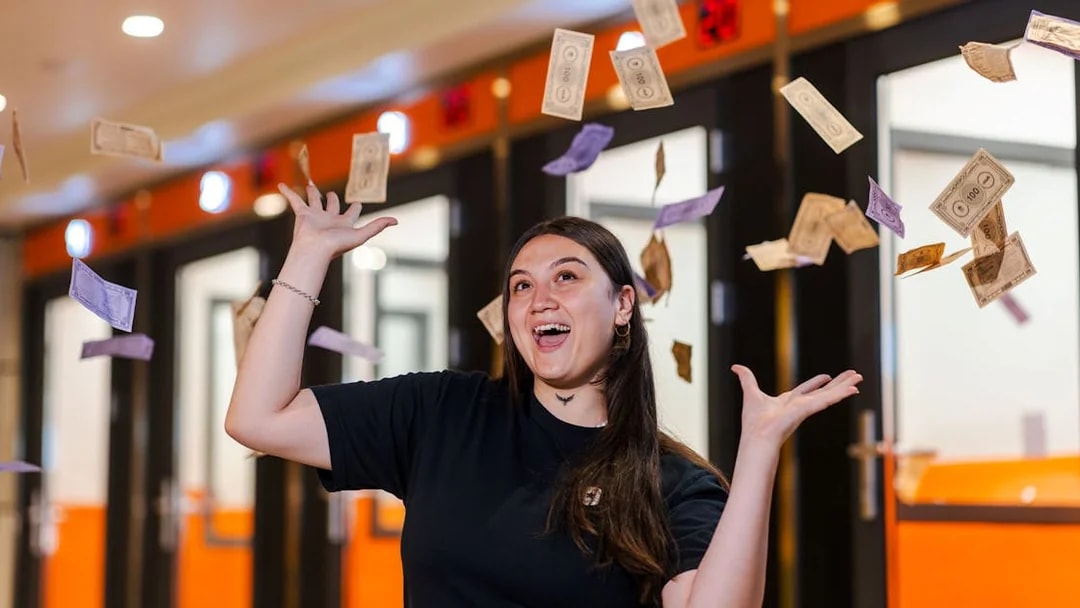 Person enjoying Monopoly Dreams Melbourne with play money in the air.