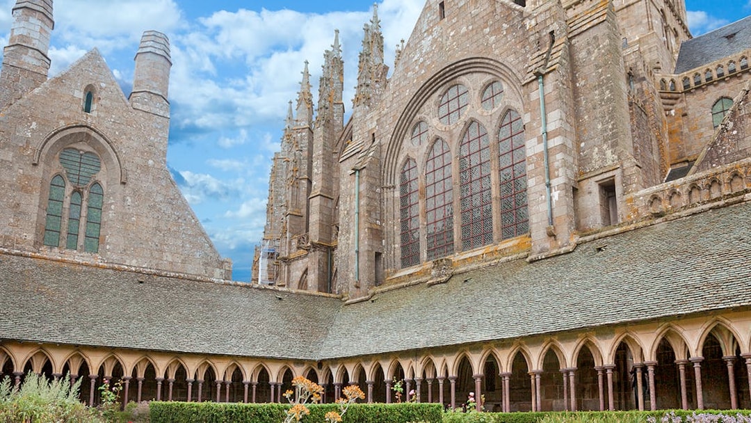 Mont-Saint-Michel Abbey cloister with stone arches and garden.