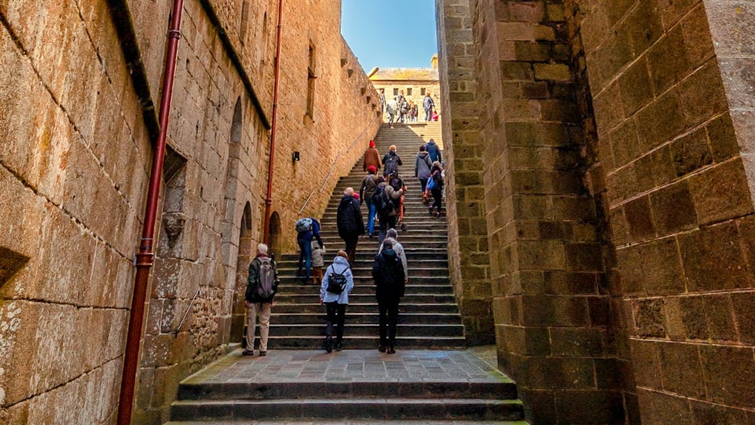Tourists ascending stone steps in Mont Saint Michel, France.