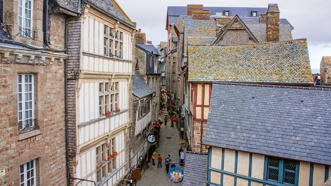 Narrow street in Mont Saint-Michel with historic stone and timber buildings, view from above.