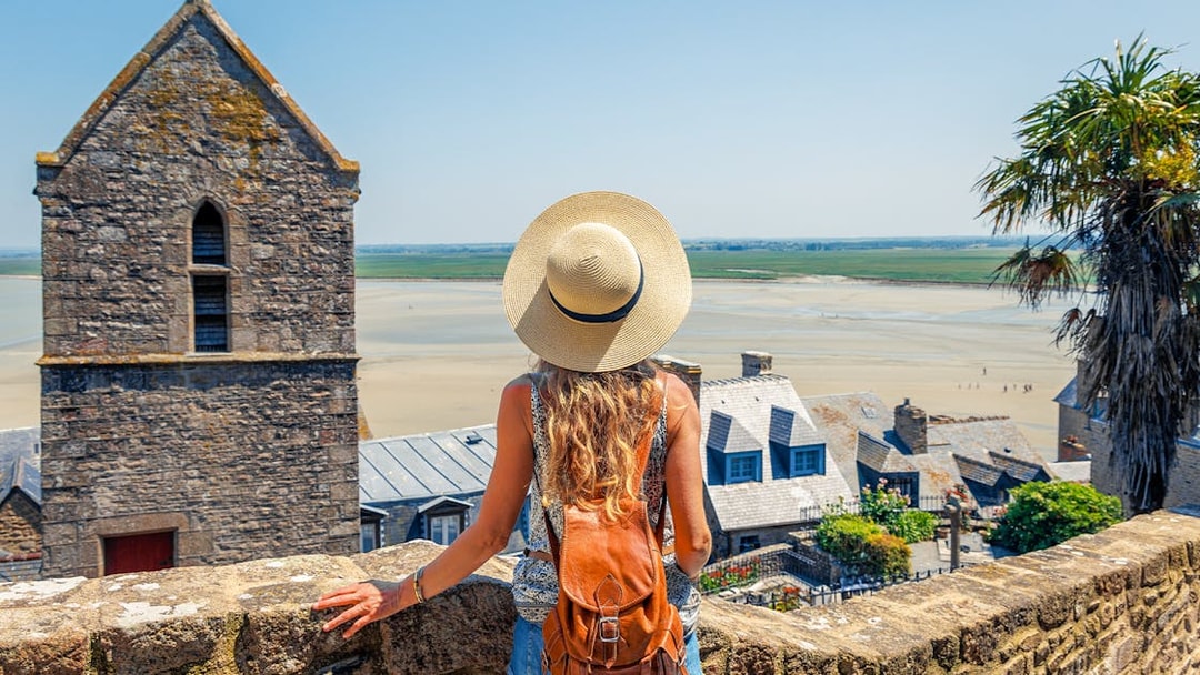 Woman with backpack overlooking Mont Saint Michel in Normandy, France.