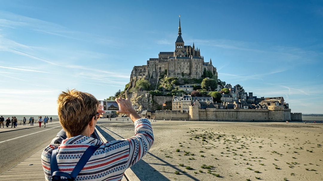 Tourist photographing Mont Saint Michel in Normandy, France.