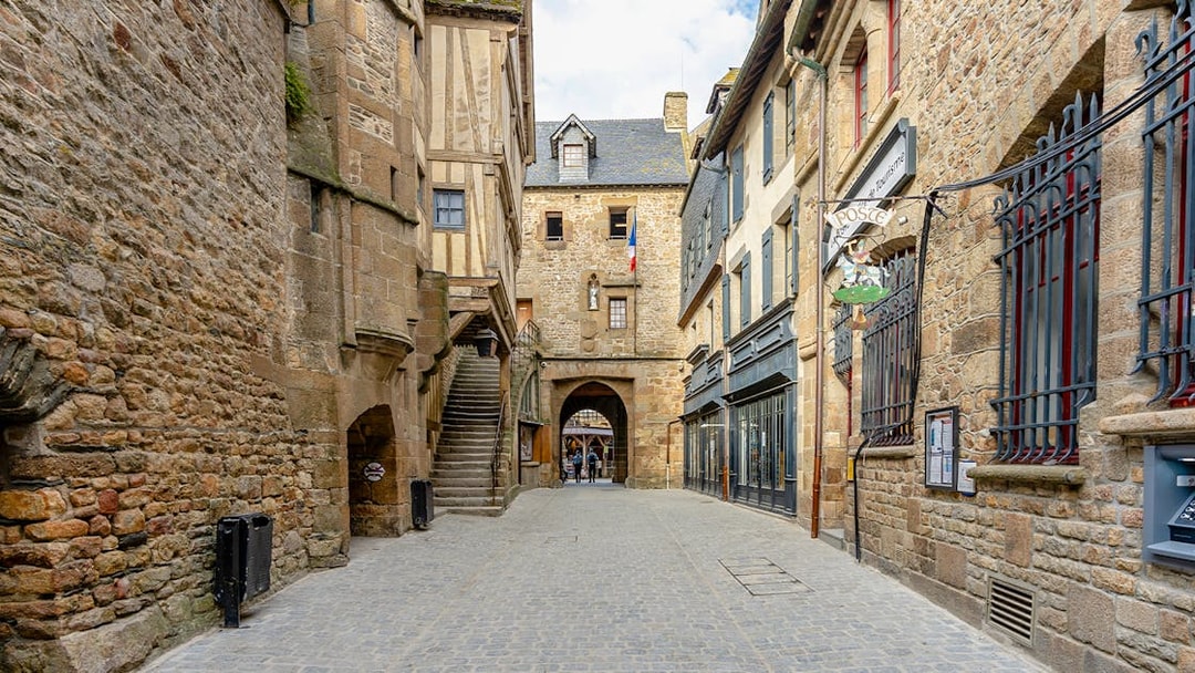 Narrow cobblestone street in Le Mont Saint Michel with historic stone buildings.