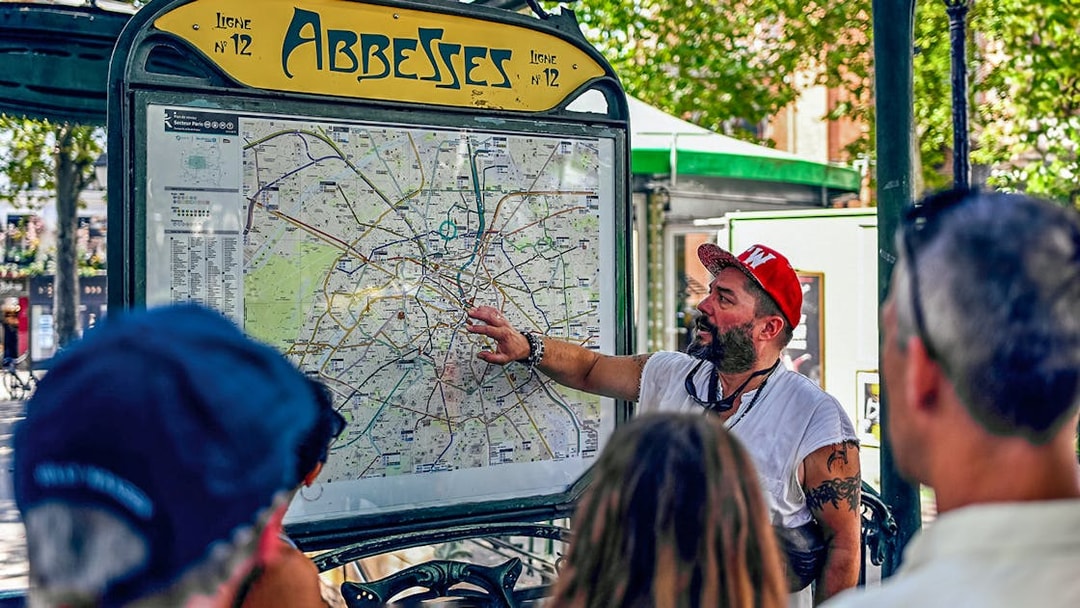 Tour guide explaining Paris map at Abbesses station during Montmartre food tour.