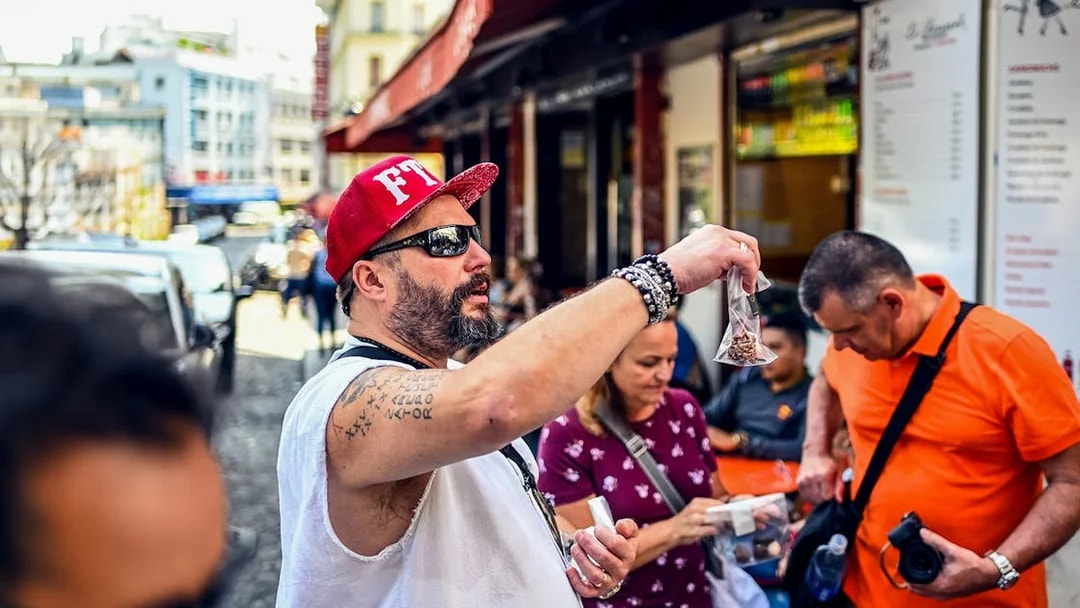 Man showcasing local snacks during a Montmartre food tour in Paris.