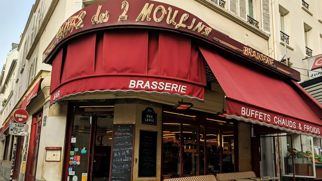 Cafe des 2 Moulins exterior with red awning on Rue Lepic, Paris.