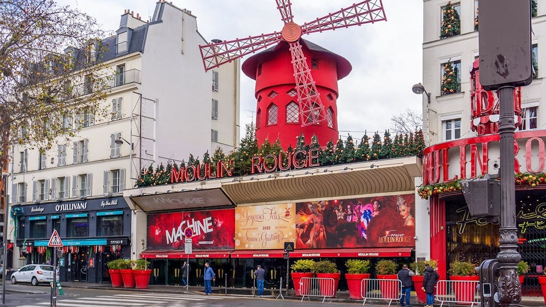 Red windmill of Moulin Rouge in Montmartre, Paris, during Montmartrain ride.